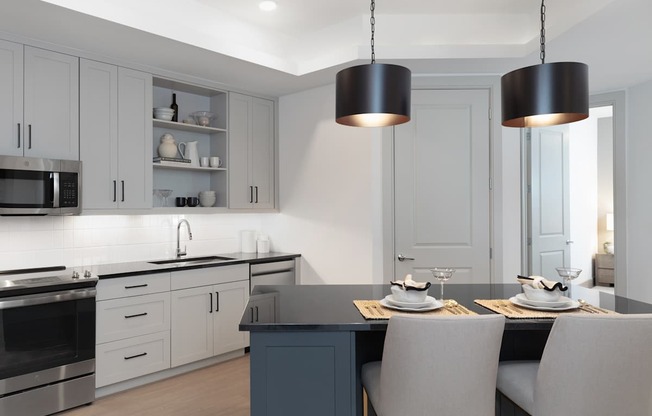 A modern kitchen with a dark countertop and white cabinets.