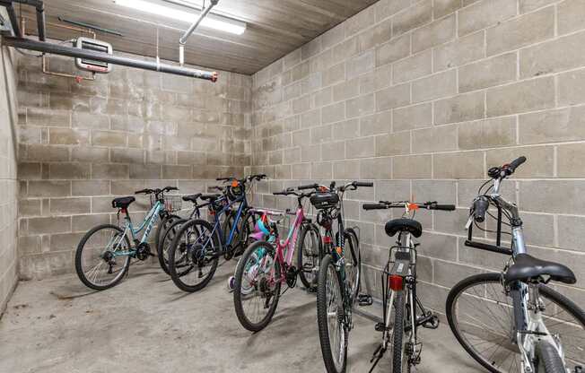 A row of bicycles are parked in a concrete room.
