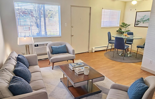 Bright and inviting living room with modern furniture, wood flooring, and a cozy dining area perfect for gatherings.