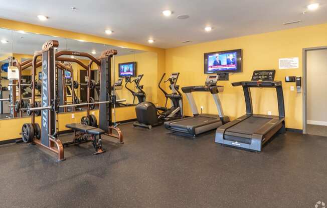 a gym with treadmills and other exercise equipment and a tv