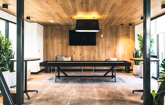 A conference room with a long table and a flat screen TV mounted on the wall.