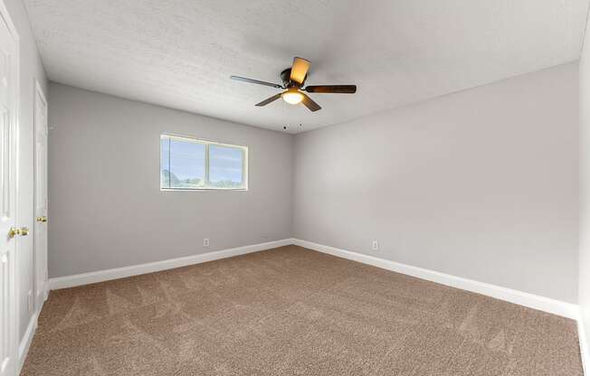 an empty room with a ceiling fan and a window