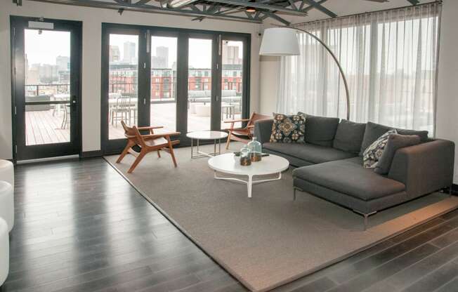 Community Room with Large Grey Sectional And Floor to Ceiling Windows at 700 Central Apartments, Minneapolis, 55414