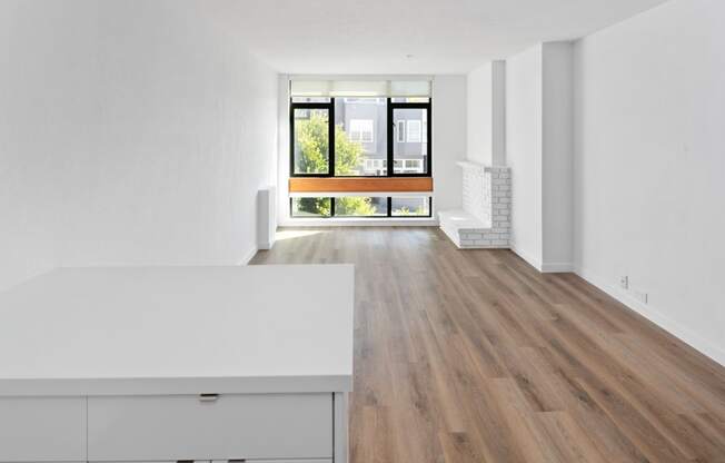 an open living room and kitchen area with white walls and hardwood floors