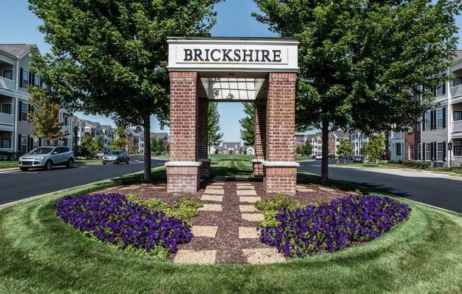 an architectural rendering of a brick building with a sign on top of a flower garden