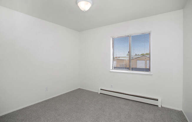 A bedroom with a large window and a grey carpet at Brookside Apartments, Springfield