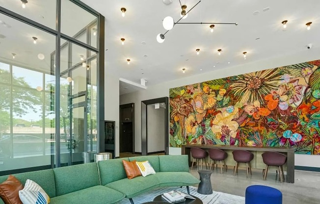 A living room with a green couch and a large mural on the wall.