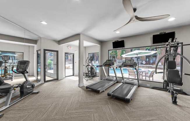 A spacious gym with treadmills, exercise bikes, and a fan.