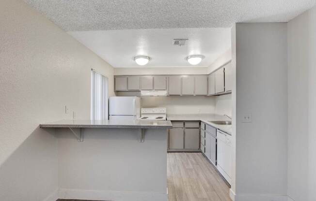 A kitchen with white cabinets and a refrigerator.