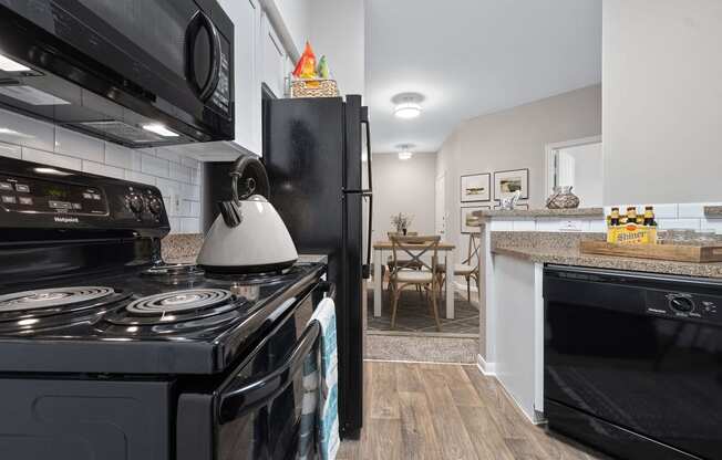 a kitchen with black appliances and a stove and a refrigerator at Fountains of Denton in Denton, TX