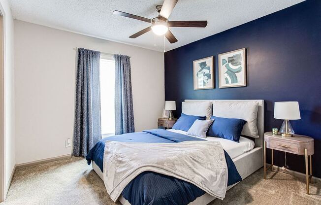 A bedroom with a bed, two lamps, and a ceiling fan.