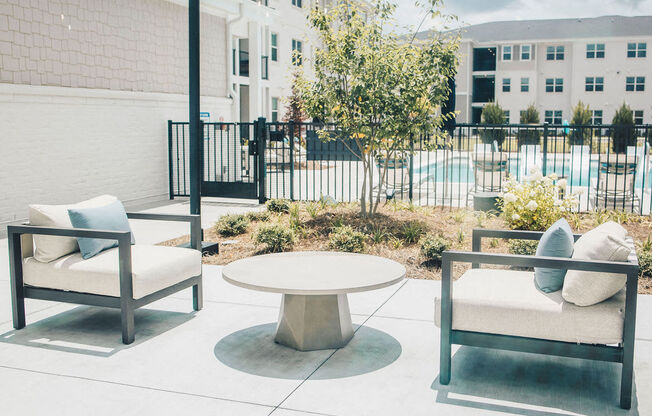 a patio with chairs and a table in front of a pool