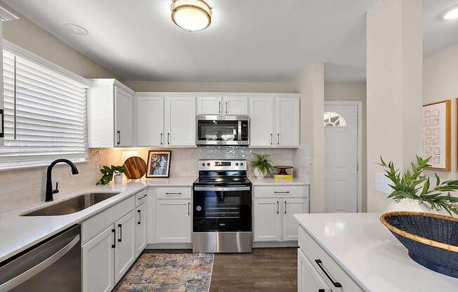 A modern kitchen with white cabinets and stainless steel appliances.
