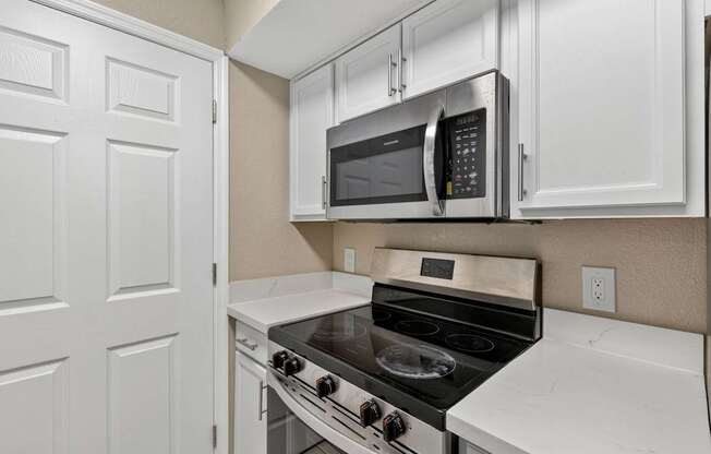 A kitchen with a stove, oven, microwave, and cabinets.