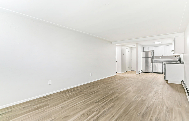 Bright, open-concept living and kitchen area featuring sleek stainless steel appliances, modern cabinetry, and stylish wood flooring.