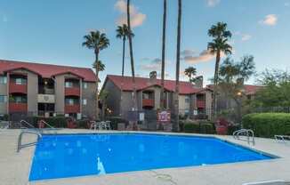 Enclave large pool view with lounging space and trees surrounding