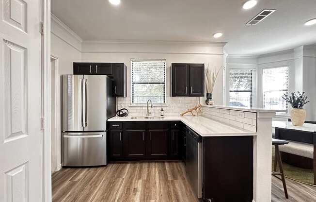 a kitchen with black cabinets and a stainless steel refrigerator