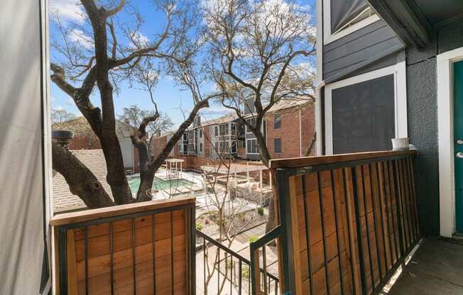 A view from a balcony looking out at a pool and houses.