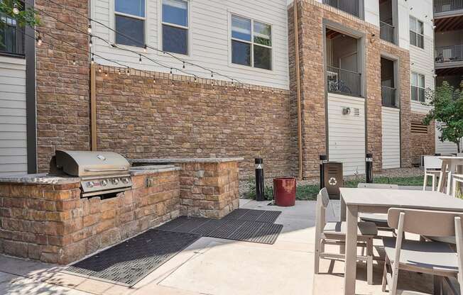 an outside patio with a grill and a table with chairs