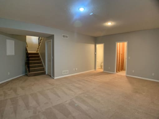a empty living room with a staircase and a carpeted floor