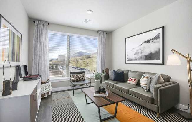 A living room with a grey couch and a painting on the wall.