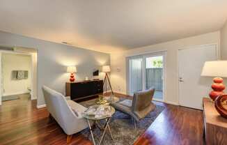 Model home living room with hardwood inspired flooring and views of the sliding glass door to patio and the front door. at Monte Bello Apartments, California