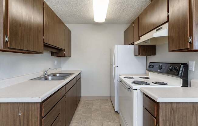 A kitchen with white appliances and brown cabinets.