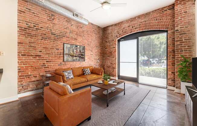 a living room with a couch and a coffee table in front of a brick wall