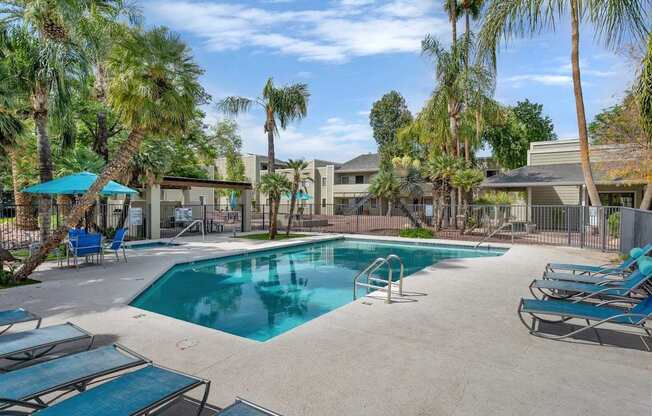 A swimming pool surrounded by palm trees and lounge chairs.