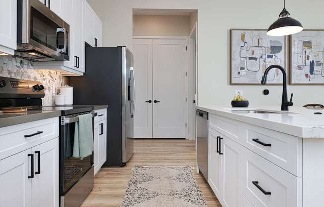 A kitchen with white cabinets and a black refrigerator.