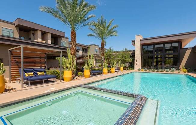 A pool surrounded by palm trees and a building.