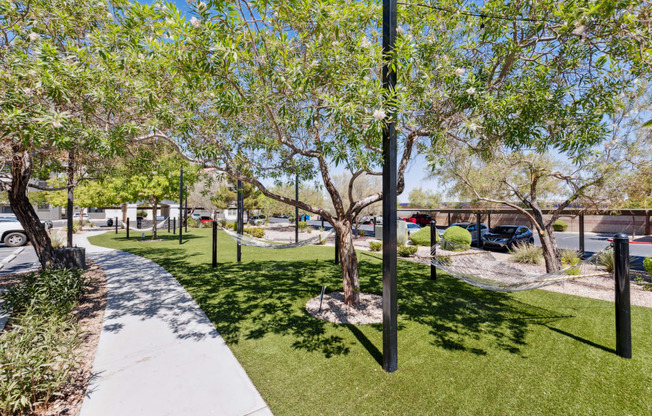 a park with green grass and trees and a sidewalk