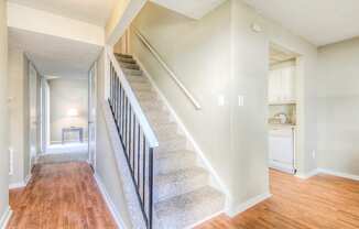 the view of a staircase in a home with white walls and wood floors