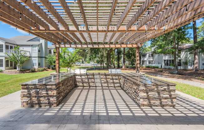 an outdoor patio with a wooden pergola and stone walls