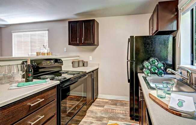 A kitchen with a black refrigerator and wooden cabinets.