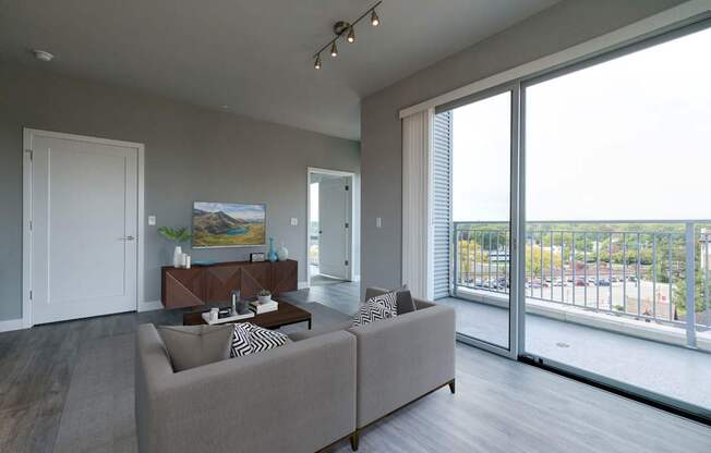 A living room with a grey couch and a painting on the wall.