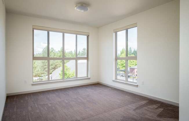 an empty living room with large windows and carpeting