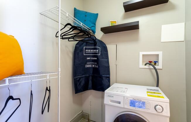 a laundry room with a washing machine and a jacket on a rack