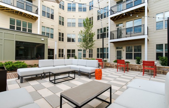 an outdoor patio with couches and tables in front of an apartment building