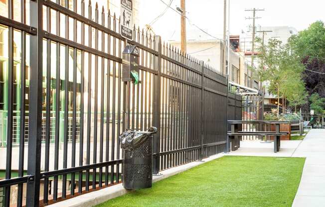a fence with a bench and trash can in front of it