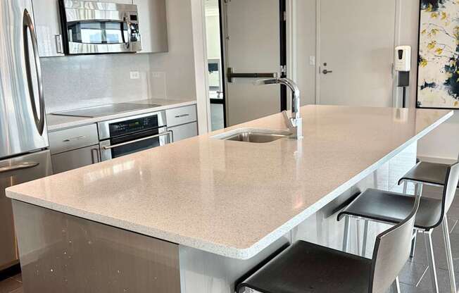 A kitchen with a white counter top and black chairs.