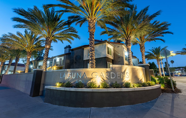 a sign in front of a building with palm trees  at Laguna Gardens Apts., Laguna Niguel