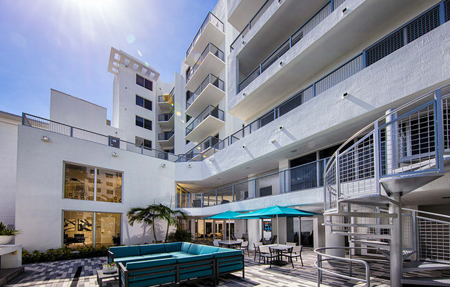 a large white building with a pool and umbrellas at Saba Pompano Beach, Pompano Beach, 33062