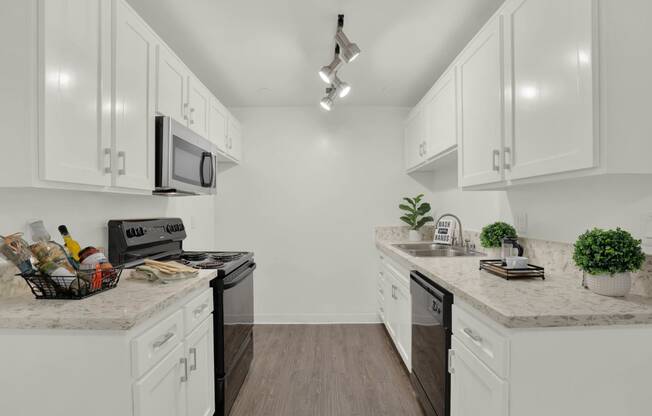 a white kitchen with white cabinets and black appliances  at Willow Tree Apartments, Torrance, CA, 90505