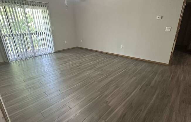 an empty living room with wood floors and a ceiling fan