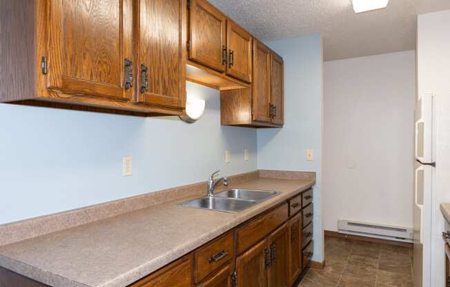 a kitchen with a sink and cabinets and a refrigerator. Fargo, ND Pacific South Apartments