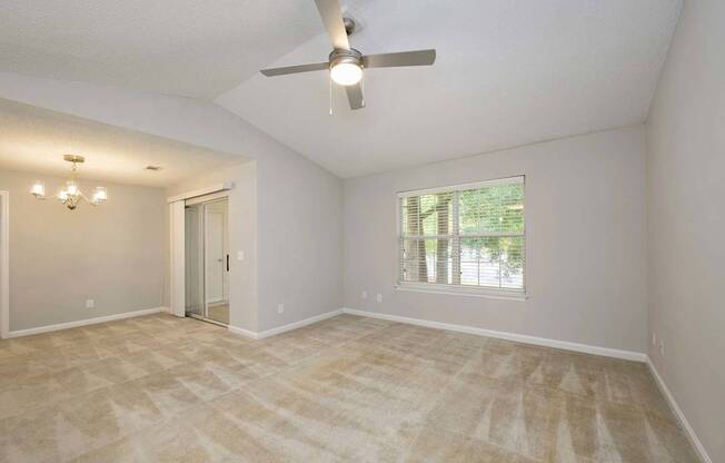 A room with a ceiling fan and a window with blinds.