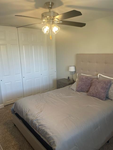 a bedroom with a white bed and a ceiling fan