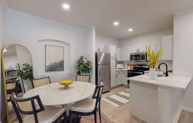 a dining area with a round table and chairs and a kitchen with stainless steel appliances