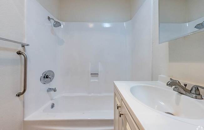 A white bathroom with a tub, sink and mirror.
